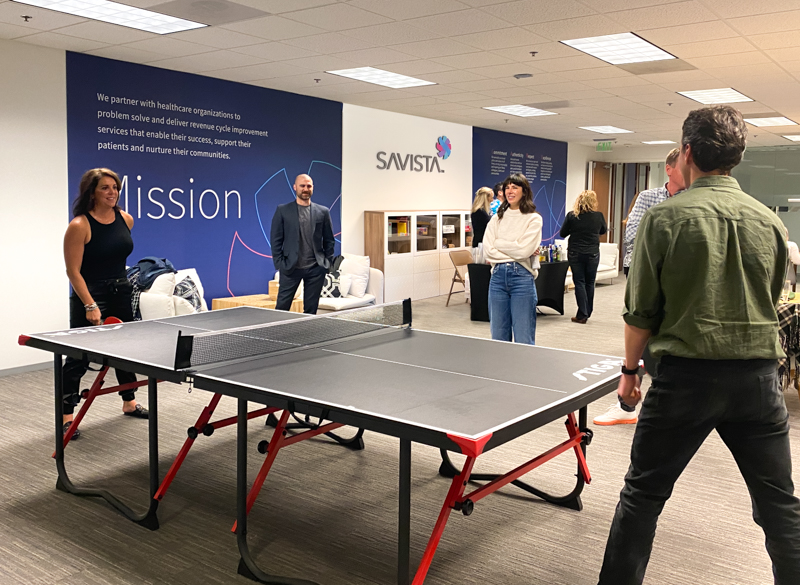 Employees playing ping pong in the Savista office